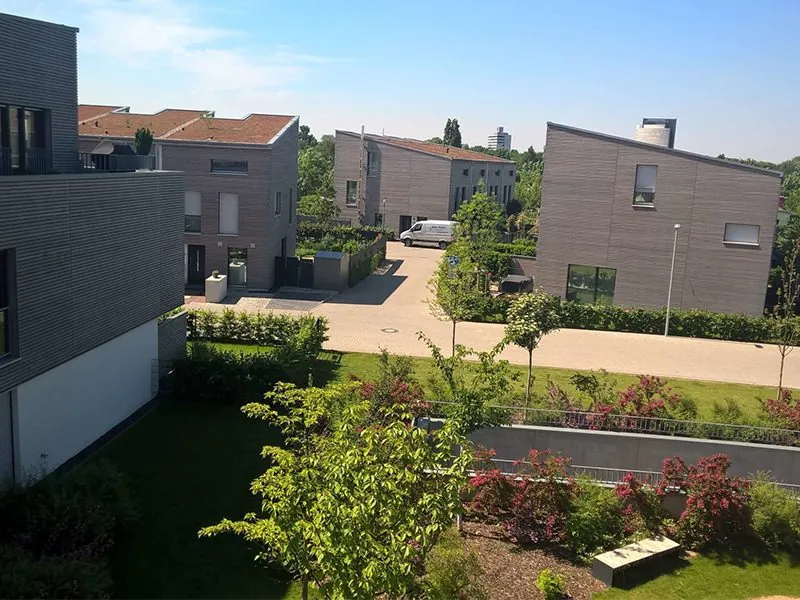 Stadthäuser mit Holzfassade und begrünten Dächern, davor ein Garten